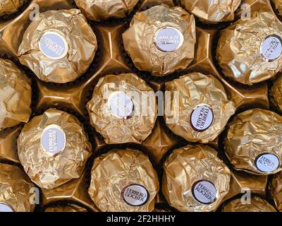 Grodno, Bielorussia - 03.09.2021: Sfondo d'oro Ferero Rocher candies primo piano. Texture di Ferero Rocher caramelle Foto Stock
