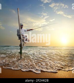 Pescatore locale su stick su una spiaggia dell'oceano indiano, Sri Lanka Foto Stock