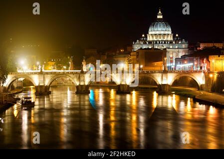 Vista notturna sul Sant' Angelo Bridge e la Basilica di San Pietro in Roma, Italia Foto Stock