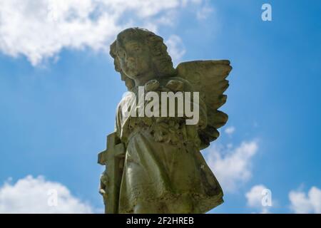 Un angelo di pietra con figurine a croce contro un cielo blu e nuvole. Al cimitero Metodista di Mt Vernon a Maces Spring, Hiltons, Virginia. Foto Stock