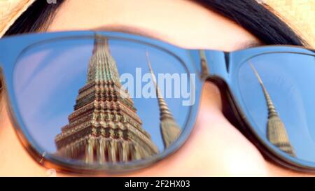 Stupas storico nel Tempio di Wat Pho, Città Vecchia di Bangkok, Thailandia che riflette sugli occhiali da sole per visitatori femminili Foto Stock