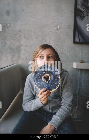 I lunghi capelli di Boy sbirciano su Donut Gigante Foto Stock