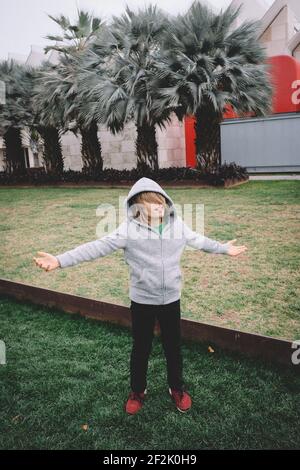 Ragazzo in cavalletti grigi con le braccia allungate Foto Stock