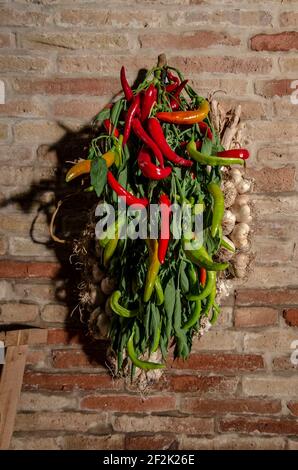 Chili e ai appesi al muro di una casa Foto Stock