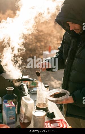 Uomo che prepara il caffè mentre esplora il Canyonlands National Park durante la vacanza Foto Stock