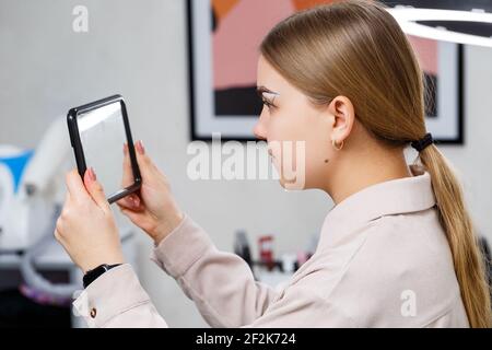 L'artista del trucco applica la tinta del sopracciglio per il trucco permanente di una ragazza giovane. Make-up professionale e cura cosmetica del viso Foto Stock