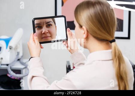 L'artista del trucco applica la tinta del sopracciglio per il trucco permanente di una ragazza giovane. Make-up professionale e cura cosmetica del viso Foto Stock