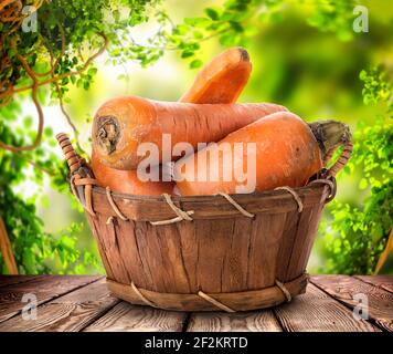 Carote fresche in un cestino su un tavolo di legno, un raccolto di verdure Foto Stock