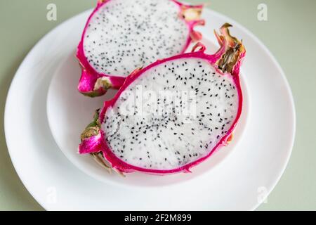 Pitahaya Dragon Fruit con polpa fresca, tagliata a metà su un piatto bianco Foto Stock