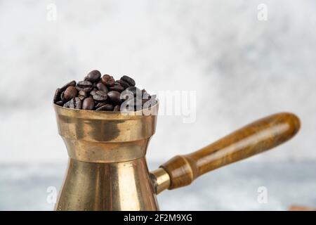 Macchina per il caffè piena di chicchi di caffè tostati su superficie in marmo Foto Stock