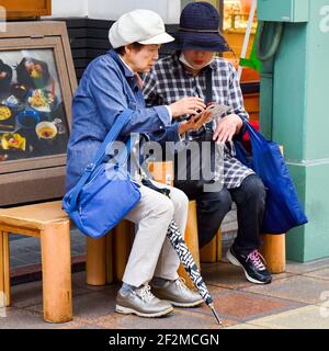 Le donne giapponesi più anziane che guardano i loro telefoni cellulari, Kyoto, Giappone Foto Stock