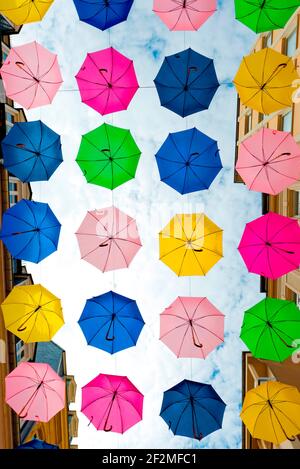 Ombrelli colorati appesi tra le case in una zona pedonale, Lussemburgo, Lussemburgo Foto Stock