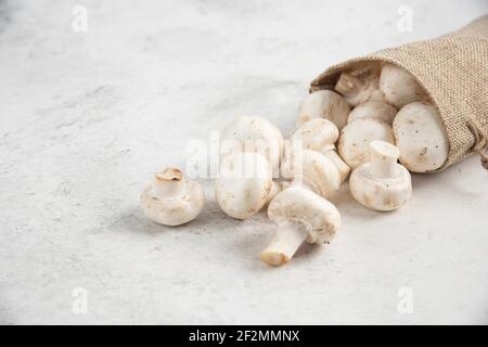 Funghi bianchi all'interno di cestini rustici su sfondo marmoreo Foto Stock