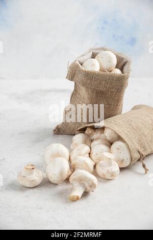 Funghi bianchi all'interno di cestini rustici su sfondo marmoreo Foto Stock