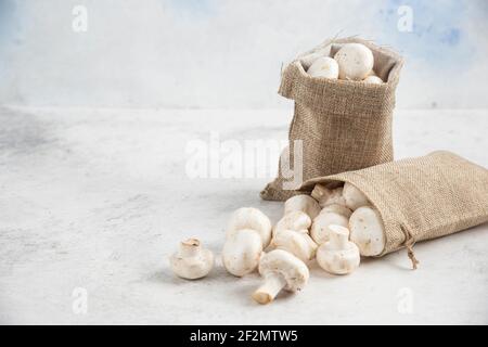 Funghi bianchi all'interno di cestini rustici su sfondo marmoreo Foto Stock