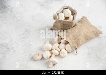 Funghi bianchi all'interno di cestini rustici su sfondo marmoreo Foto Stock