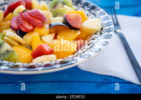 Insalata di frutta naturale e sana con arancia in un piatto vintage su una superficie rustica blu. Concetto di cibo sano, vita sana. vista a 45 gradi, Foto Stock