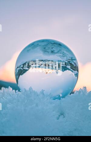 l'antico borgo di vinigo visto attraverso una palla di cristallo che riposa sulla neve ghiacciata. Borca di cadore, provincia di belluno, dolomiti, veneto, italia Foto Stock