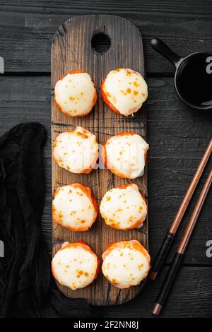 Involtini di sushi giapponesi denominati EBI al forno con wasabi e pesce di salmone set, su sfondo di legno nero tavolo, vista dall'alto piatto Foto Stock