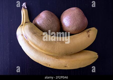 Banane e kiwi su sfondo nero Foto Stock