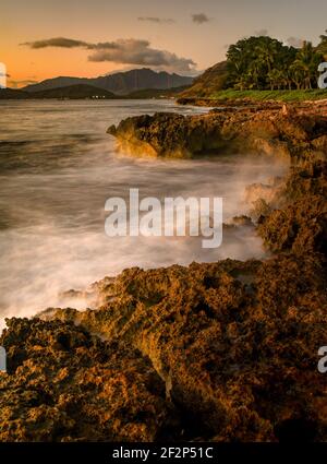 Tramonto spettacolare a Paradise Cove, onde dell'Oceano Pacifico che si infrangono su rocce vulcaniche lungo la costa idilliaca, Kapolei, Oahu, Hawaii, USA Foto Stock