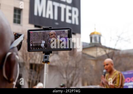 Washington, DC, USA, 12 marzo 2021. Nella foto: Un uomo in streaming le osservazioni di Ayanna Pressley al rally 100 Donne in 100 giorni live su Instagram via smartphone. Il rally è stato sponsorizzato dal Consiglio Nazionale per le donne e le ragazze incarcerate e precedentemente incarcerate. E ha cercato di esercitare pressioni sul presidente Joe Biden per concedere clemenza a 100 donne nelle prigioni federali durante il suo primo 100 dau=ys in carica. Credit: Alison C Bailey/Alamy Live News Foto Stock