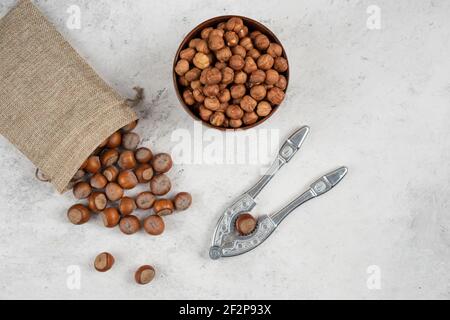 Sgusciati organici e nocciole in burlap con cracking attrezzo Foto Stock