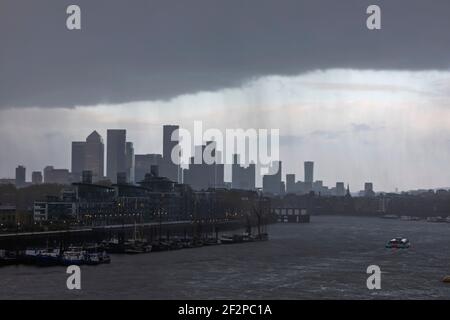 Inghilterra, Londra, Docklands, Fiume Tamigi e Canary Wharf Skyline in un giorno bagnato nuvoloso Foto Stock