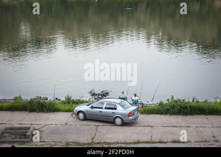 SZEGED, UNGHERIA - 21 LUGLIO 2017: Due uomini, un maschio anziano e uno giovane, rilassati e pesca sul fiume Tisza di notte, il rivivatore principale che passa Foto Stock