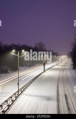 Germania, Sassonia-Anhalt, Magdeburgo, autostrada cittadina innevata con sentieri leggeri dalle auto. Foto Stock