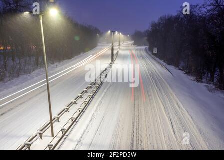 Germania, Sassonia-Anhalt, Magdeburgo, autostrada cittadina innevata con sentieri leggeri dalle auto. Foto Stock