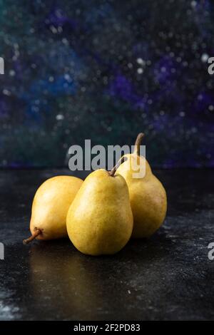 Tre gustose pere gialle poste sulla superficie nera Foto Stock