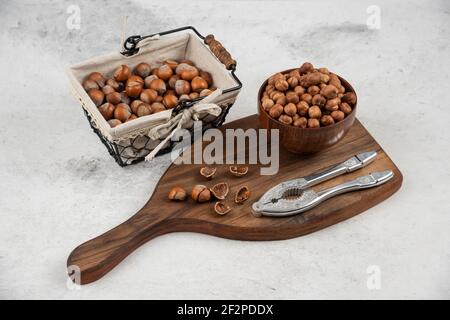 Mucchio di nocciole sgusciate organiche in cestino e nocciole su asse di legno Foto Stock