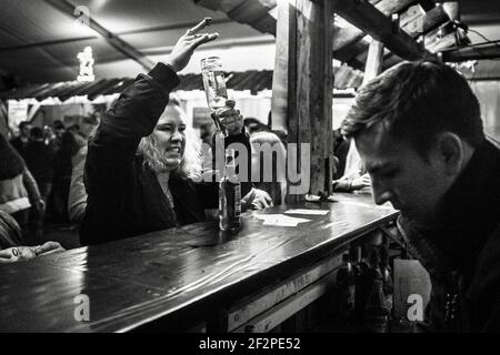 Germania, Baviera, Antdorf, settimana del festival dell'associazione dei costumi tradizionali. Giovane donna che riempie due bottiglie di birra durante la festa nel marchese. Foto Stock