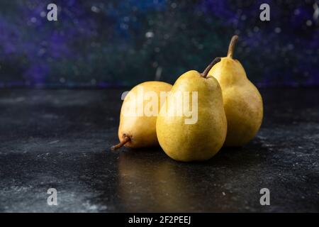 Tre gustose pere gialle poste sulla superficie nera Foto Stock
