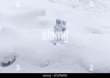 La statuetta di un astronauta esplora con sicurezza la superficie del pianeta alieno. Pianeta freddo coperto di neve. Spazio di copia. Foto Stock