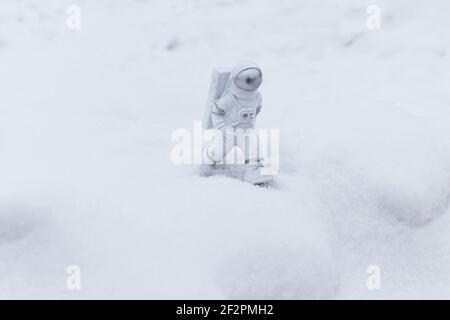 La statuetta di un astronauta esplora con sicurezza la superficie del pianeta alieno. Pianeta freddo coperto di neve. Spazio di copia. Foto Stock