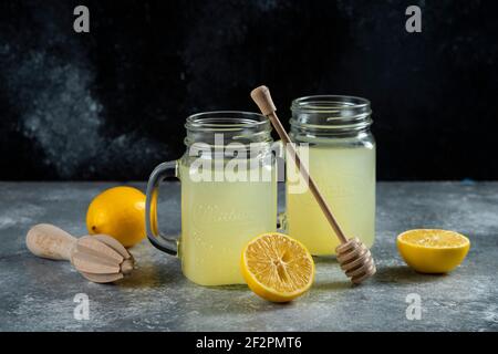 Due vasetti di vetro di succo di limone e fette su un sfondo in marmo Foto Stock