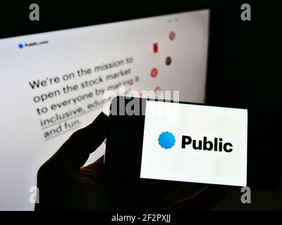 Persona che detiene smartphone con logo della piattaforma di investimento Public.com (Public Holdings Inc.) sullo schermo davanti al sito Web. Mettere a fuoco il display del telefono. Foto Stock