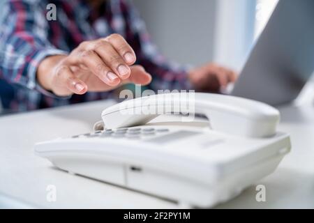 primo piano mano di uomo d'affari sta raccogliendo il ricevitore del telefono in ufficio. Foto Stock