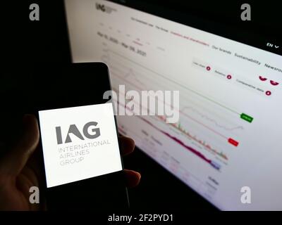 Persona che detiene uno smartphone con il logo della compagnia aerea International Airlines Group (IAG) sullo schermo davanti al sito Web. Mettere a fuoco il display del telefono. Foto Stock