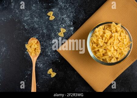 Ciotola di pasta cruda su tovaglia con cucchiaio Foto Stock