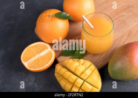 Bicchiere di succo d'arancia e mango fresco e fetta di succo frutta arancione su sfondo scuro Foto Stock