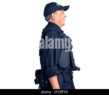 Uomo anziano bello che indossa uniforme della polizia guardando a lato, rilassa il profilo posa con viso naturale con sorriso sicuro. Foto Stock