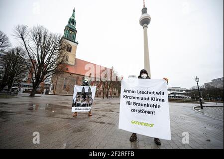 13 marzo 2021, Berlino: Gli attivisti di Greenpeace protestano davanti alla Chiesa di Santa Maria e alla torre della televisione con un banner che recita "Armin Laschet vuole distruggere le chiese e il clima per la lignite". Gli attivisti di Greenpeace stanno manifestando in tutta la Germania contro la politica del carbone della CDU. L'occasione è la prossima decisione sull'ulteriore estrazione di lignite nella Renania settentrionale-Vestfalia. Foto: Fabian Sommer/dpa Foto Stock