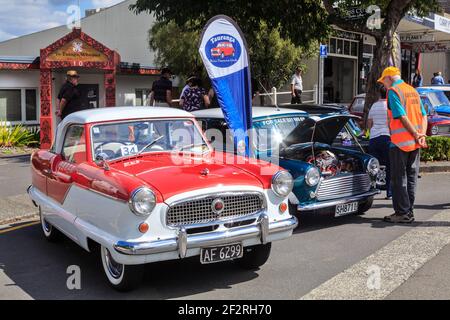 Un paio di auto classiche, un Metropolitan di Austin del 1958 e un Morris Mini del 1981, affiancati a una mostra di auto all'aperto Foto Stock