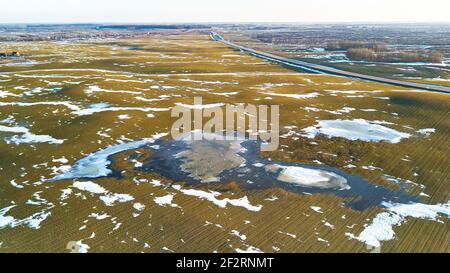 Vista aerea dei campi a molla. Scioglimento della neve, piscine d'acqua sui prati. Cambio di stagione. Marzo paesaggio rurale. Raccolti invernali e paesaggio arato campo. Bielorussia Foto Stock
