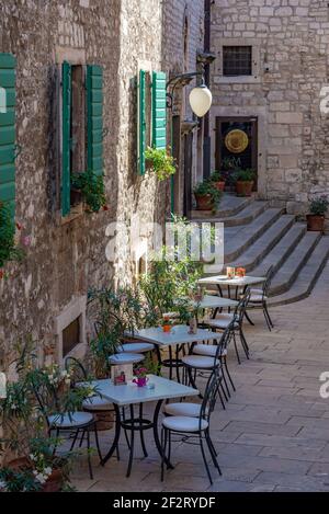 Tavoli da ristorante in una strada stretta nella città vecchia di Sibenik, Croazia Foto Stock