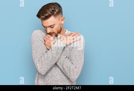 Giovane uomo rosso che indossa un maglione invernale casual abbracciandosi felice e positivo, sorridente sicuro. Auto amore e cura di sé Foto Stock