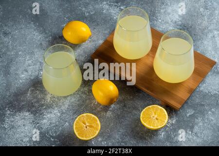 Tre tazze di vetro con succo di limone fresco su un legno scheda Foto Stock